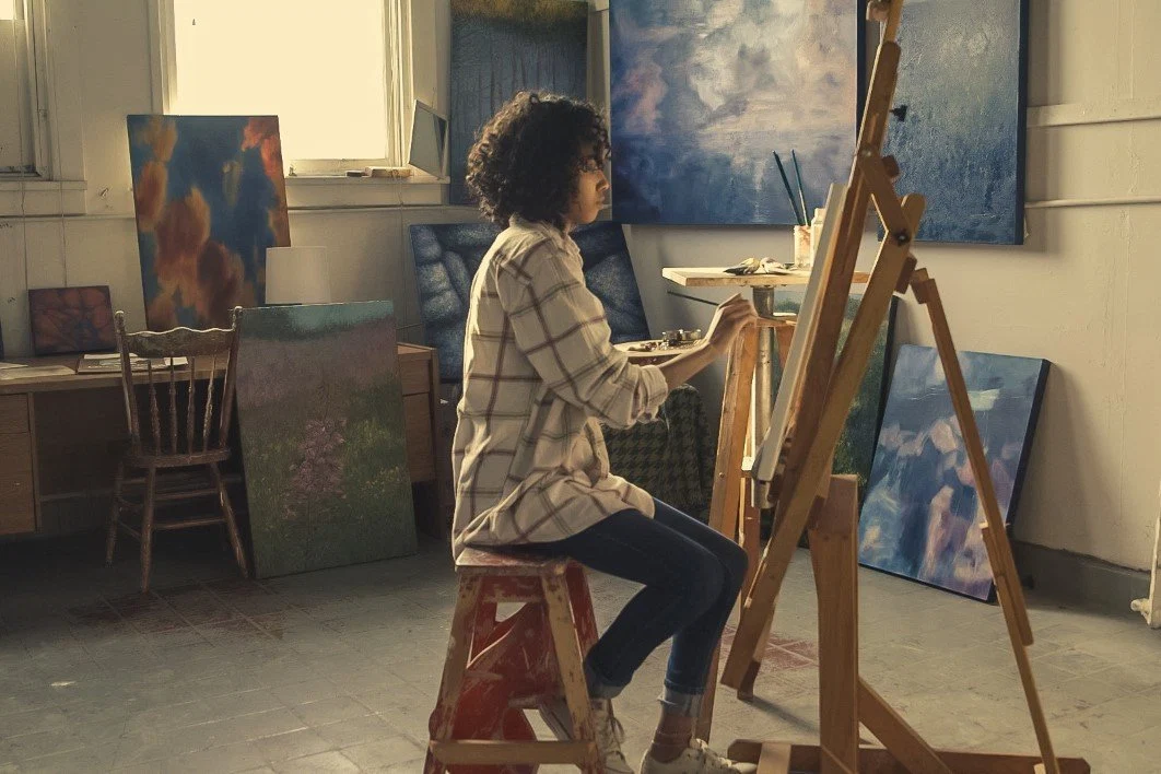Film still — a painter at an easel in the studio